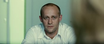 Movie still from “The Wave” (2008), directed by Dennis Gansel – A man in a white shirt is looking at the camera; Close Up shot, Low angle