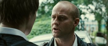 Movie still from “The Wave” (2008), directed by Dennis Gansel – A man in a leather jacket talking to another man in front of a car; Close Up shot, Over the shoulder angle