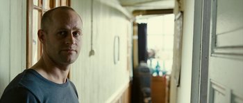 Movie still from “The Wave” (2008), directed by Dennis Gansel – A man standing in front of a wall in a room; Close Up shot, Over the shoulder angle