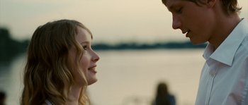 Movie still from “The Wave” (2008), directed by Dennis Gansel – A young girl smiles at a man on the beach; Close Up shot, Over the shoulder angle