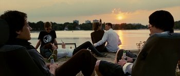 Movie still from “The Wave” (2008), directed by Dennis Gansel – A group of people sitting next to each other on the beach; Wide shot, Over the shoulder angle
