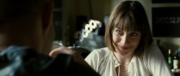 Movie still from “The Wave” (2008), directed by Dennis Gansel – A woman smiles at the camera as a man sits next to her; Close Up shot, Over the shoulder angle