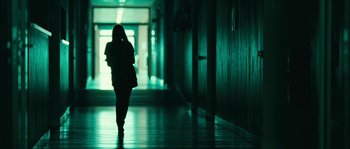 Movie still from “The Wave” (2008), directed by Dennis Gansel – A woman is walking down the hallway of a building at night; Wide shot, Low angle