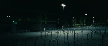 Movie still from “The Wave” (2008), directed by Dennis Gansel – A man standing in a parking lot at night; Extreme Wide shot, High angle