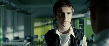 Movie still from “The Wave” (2008), directed by Dennis Gansel – A young man in a white t - shirt and a black vest; Close Up shot, Low angle