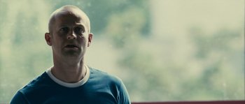 Movie still from “The Wave” (2008), directed by Dennis Gansel – A man with a bald head wearing a blue t - shirt; Close Up shot, Low angle