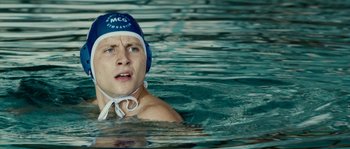 Movie still from “The Wave” (2008), directed by Dennis Gansel – A man swimming in the water wearing a blue and white hat; Close Up shot, Low angle