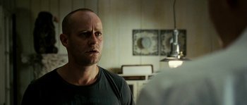 Movie still from “The Wave” (2008), directed by Dennis Gansel – A man in a black t - shirt is standing in front of a mirror; Close Up shot, Over the shoulder angle
