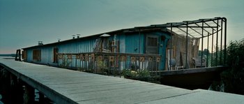 Movie still from “The Wave” (2008), directed by Dennis Gansel – A wooden dock with a blue building in the background; Extreme Wide shot, Low angle