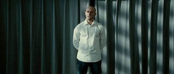 Movie still from “The Wave” (2008), directed by Dennis Gansel – A man standing in front of a window with his hands on his hips; Medium shot, Low angle