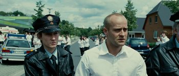 Movie still from “The Wave” (2008), directed by Dennis Gansel – A man in a white shirt is walking down the street; Close Up shot, Over the shoulder angle