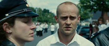 Movie still from “The Wave” (2008), directed by Dennis Gansel – A man in a white shirt and a man in a black hat; Close Up shot, Over the shoulder angle