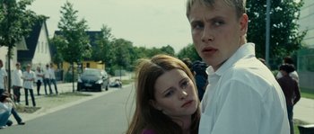 Movie still from “The Wave” (2008), directed by Dennis Gansel – A man and a woman standing next to each other on the side of a road; Close Up shot, Low angle