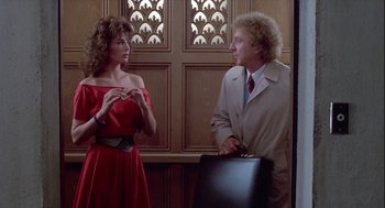 Movie still from “The Woman in Red” (1984), directed by Gene Wilder – A woman in a red dress talking to a man in a tan suit; Medium shot, Over the shoulder angle