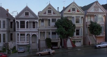 Movie still from “The Woman in Red” (1984), directed by Gene Wilder – A car parked in front of a row of houses on a street; Extreme Wide shot, High angle