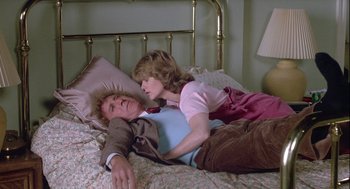 Movie still from “The Woman in Red” (1984), directed by Gene Wilder – A man and a woman laying on a bed together; Medium shot, High angle