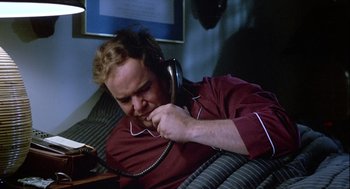 A man sitting on top of a couch talking on a phone
