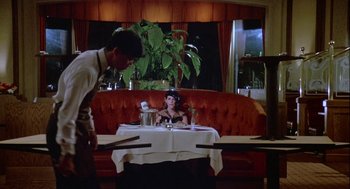 Movie still from “The Woman in Red” (1984), directed by Gene Wilder – A woman sitting at a table in front of a man; Wide shot, Low angle