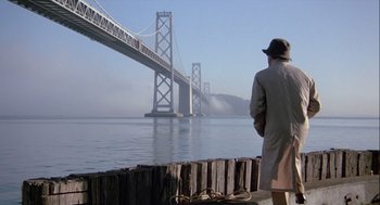 Movie still from “The Woman in Red” (1984), directed by Gene Wilder – A man standing on a pier looking at a bridge; Wide shot, Low angle