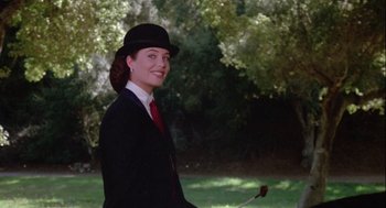 Movie still from “The Woman in Red” (1984), directed by Gene Wilder – A woman in a suit and hat holding a stick; Medium shot, Low angle