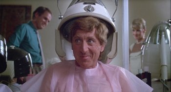 Movie still from “The Woman in Red” (1984), directed by Gene Wilder – A man sitting in a chair with a hair dryer on his head; Close Up shot, Over the shoulder angle