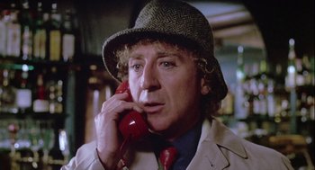 Movie still from “The Woman in Red” (1984), directed by Gene Wilder – A man in a hat talking on a red phone; Close Up shot, Low angle