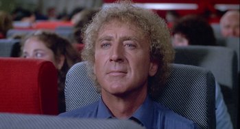 Movie still from “The Woman in Red” (1984), directed by Gene Wilder – A person sitting in a chair; Close Up shot, Over the shoulder angle