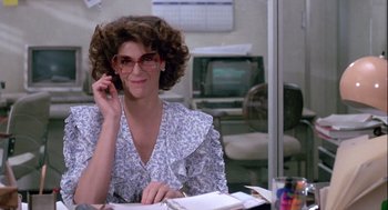 Movie still from “The Woman in Red” (1984), directed by Gene Wilder – A woman sitting at a table with a phone; Medium shot, Low angle