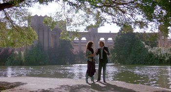 Movie still from “The Woman in Red” (1984), directed by Gene Wilder – A man and a woman standing next to a body of water; Wide shot, Low angle