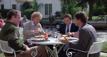 Movie still from “The Woman in Red” (1984), directed by Gene Wilder – A group of people sitting at a table eating food; Wide shot, Over the shoulder angle