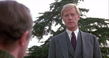 Movie still from “The Woman in Red” (1984), directed by Gene Wilder – A man wearing a suit and tie in front of a tree; Close Up shot, Low angle