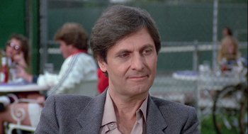 Movie still from “The Woman in Red” (1984), directed by Gene Wilder – A person wearing a suit and tie; Close Up shot, Over the shoulder angle