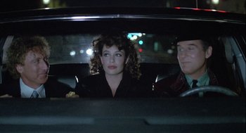 Movie still from “The Woman in Red” (1984), directed by Gene Wilder – A woman sitting in the back seat of a car; Medium shot, Over the shoulder angle