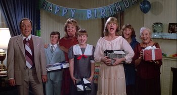 Movie still from “The Woman in Red” (1984), directed by Gene Wilder – A group of people standing next to each other holding gifts; Medium shot, Low angle