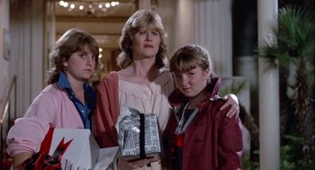 Movie still from “The Woman in Red” (1984), directed by Gene Wilder – A woman and two girls holding presents in a mall; Medium shot, Low angle