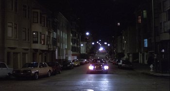 Movie still from “The Woman in Red” (1984), directed by Gene Wilder – A street at night filled with lots of traffic; Extreme Wide shot, High angle