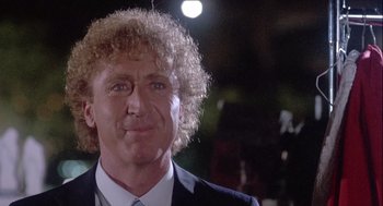 Movie still from “The Woman in Red” (1984), directed by Gene Wilder – A person wearing a suit and tie; Close Up shot, Over the shoulder angle