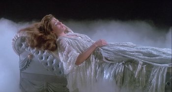 Movie still from “The Woman in Red” (1984), directed by Gene Wilder – A woman in a white dress is laying on a couch; Medium shot, High angle