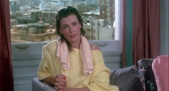 Movie still from “The Woman in Red” (1984), directed by Gene Wilder – A woman sitting on top of a couch in a room; Medium shot, Over the shoulder angle