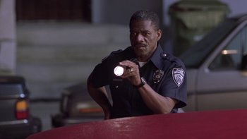 Movie still from “The Wood” (1999), directed by Rick Famuyiwa – A police officer is holding a flashlight in his hand; Close Up shot, Low angle