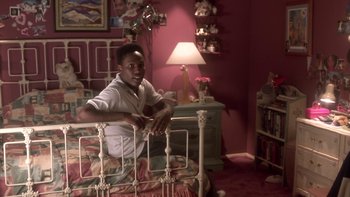 Movie still from “The Wood” (1999), directed by Rick Famuyiwa – A young boy sitting on a bed in a bedroom; Medium shot, High angle