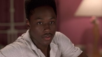 Movie still from “The Wood” (1999), directed by Rick Famuyiwa – A man with a beard is sitting in front of a pink wall; Close Up shot, High angle