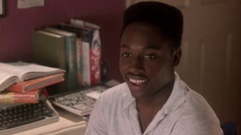 Movie still from “The Wood” (1999), directed by Rick Famuyiwa – A man sitting in front of a table with books on top of it; Close Up shot, High angle
