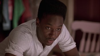 Movie still from “The Wood” (1999), directed by Rick Famuyiwa – A man with a white t - shirt is looking at the camera; Close Up shot, Low angle