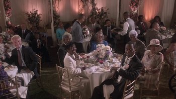 Movie still from “The Wood” (1999), directed by Rick Famuyiwa – A group of people sitting at a table with plates of food on it; Wide shot, High angle