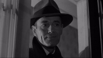 Movie still from “The Wrong Man” (1956), directed by Alfred Hitchcock – An older man wearing a hat and a suit; Close Up shot, Low angle