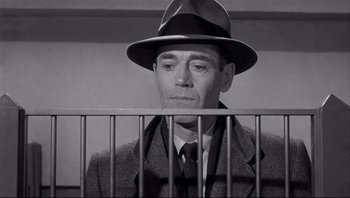Movie still from “The Wrong Man” (1956), directed by Alfred Hitchcock – A man wearing a hat and a coat; Close Up shot, Low angle