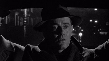 Movie still from “The Wrong Man” (1956), directed by Alfred Hitchcock – A black and white photo of a man wearing a hat; Close Up shot, Low angle