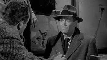 Movie still from “The Wrong Man” (1956), directed by Alfred Hitchcock – An old photo of a man in a suit and hat; Close Up shot, Over the shoulder angle