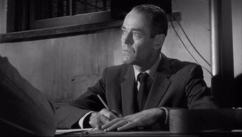 Movie still from “The Wrong Man” (1956), directed by Alfred Hitchcock – Black and white photograph of a man in a suit and tie; Close Up shot, Low angle
